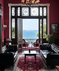 Living room with bay view, elegant decor, black leather sofas, and red accents creating a classic ambiance.