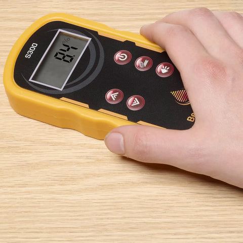 Hand holding Pinless Wood Moisture Meter S300 With Shallow Scan, 0.25 Inch Readings; digital display on wooden surface