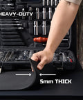 Person lifting corner of Heavy Duty EVA Workbench Mat 24x72 Inches 5mm Thick Super Grippy Garage Workshop Pad in front of tools