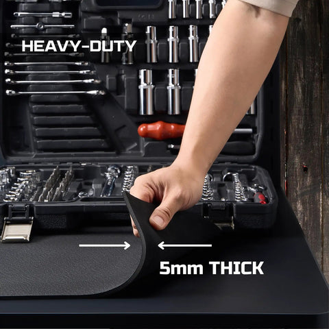 Close-up of hand lifting edge of Beefy 24x48 Inch EVA Workbench Mat, showing 5mm thickness next to a tool box in a garage