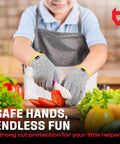 Child using Kids Cutting Gloves XS 8-12 Years - Food Grade Safety, Level 5 Cut Protection, slicing tomato, wearing gray apron.