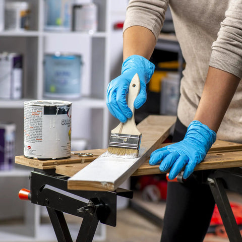 Person painting wood while wearing Blue Disposable Vinyl Gloves 100 Count Powder Free And Latex Free Comfy Flexible Fit
