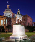 Historic equestrian statue in front of a lit-up government building at night