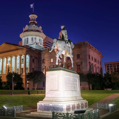 Historic equestrian statue in front of a lit-up government building at night