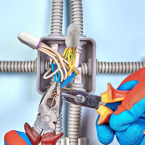 Front view of open electrical junction box with bundled wires and diagonal pliers held by gloved hands.