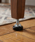 Close-up of T Nut leveling foot on wood floor, part of 12 Pack T Nut Leveling Feet for Cabinets and Desks, Adjustable Furniture Levelers.