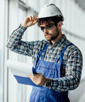 Man in plaid shirt and hard hat wearing Tough As Nails Wraparound Safety Glasses For Men And Women 12 Pack Gradient Gray, reviewing plans.