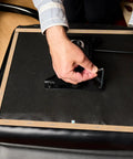 Person using Professional Grade Upholstery Tack Strip Half Inch Wide By Seventy Yards Long to secure fabric on chair.