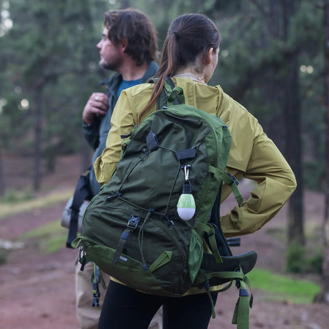 Rechargeable Camping Light With Clip Hook attached to green backpack during outdoor adventure
