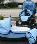 Light blue baby stroller set with carriage, seat, and matching diaper bag, parked outdoors on asphalt surface.