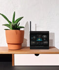 Atlas Pro Weather Station With Direct To Wi Fi HD Display Lightning Detection next to a potted plant on a desk.