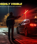 Person guiding car with 6-Piece 21-Inch Traffic Control Wand With 3 Flashing Modes Safety Baton Light, night scene.