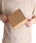 Person holding a 6x6x2 inch Rock Solid 50 Pack Small Shipping Box, brown kraft corrugated cardboard for packaging.