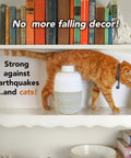 Cat on shelf with vase secured by Clear Museum Wax Two Ounce For Keeping Antiques And Collectibles From Falling On Wood Surfaces Easy To Apply And Remove Non Toxic Reusable Conservator Grade