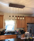 Six Light Wood Pendant Light for Kitchen Island With Industrial Black Metal Cage Shades in kitchen setting