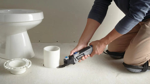 Person using Universal Flush Cutting Blade Kit For Oscillating Multitools Quick Fit Blades to cut floor near toilet