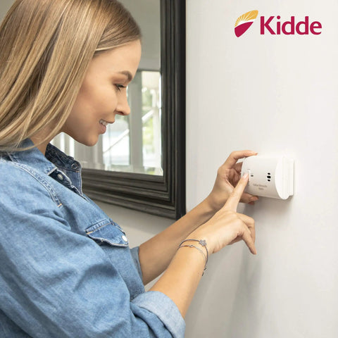 Carbon Monoxide Detector Battery Powered For Travel Or Home With 85 Decibel Alarm And LED Status Indicators Electrochemical Sensor No Wiring Required Two AA Batteries Included installed on wall with woman testing it