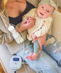 Powerhouse Rechargeable Cordless Breast Pump With Hospital Strength Suction And Dual Adjustable Settings used by mom holding baby in cozy setting.