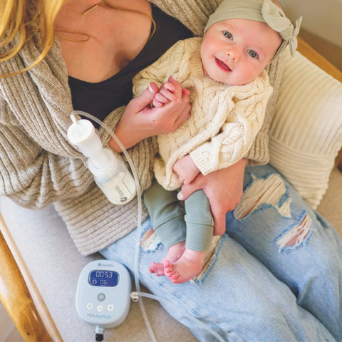 Powerhouse Rechargeable Cordless Breast Pump With Hospital Strength Suction And Dual Adjustable Settings used by mom holding baby in cozy setting.