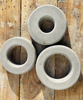 Concrete donut shapes created with Donut Sprinkler Head Mold For Concrete And Garden Decor Reusable Plastic Form With Large 8 Inch Hole DIY Donut Protector Guard For Sprinkler Heads Up To Four And Seven Eighths Inches Easy To Use For Home Projects, resting on a wooden surface.