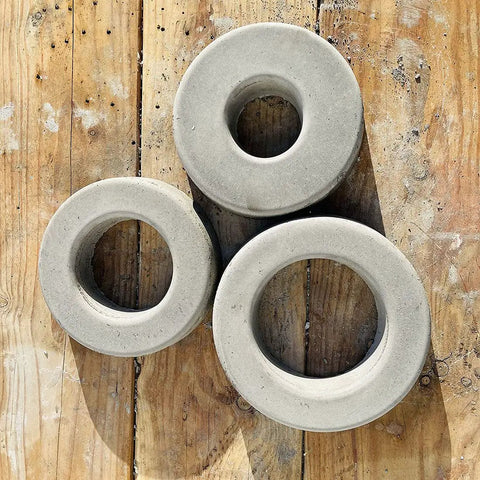 Concrete donut shapes created with Donut Sprinkler Head Mold For Concrete And Garden Decor Reusable Plastic Form With Large 8 Inch Hole DIY Donut Protector Guard For Sprinkler Heads Up To Four And Seven Eighths Inches Easy To Use For Home Projects, resting on a wooden surface.