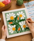 Person using a punch needle tool on a 9.8-inch frame with a daisy design, part of a Beginner Punch Needle Kit With 9.8 Inch Frame, All In One Yarn Craft Set For Adults, Includes Punch Needle Tool, Scissors, Colorful Yarn And Simple Instructions, Green.