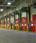 Interior view of loading bays with red doors and yellow bollard post covers for protection in a warehouse.