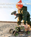 Child playing with All Terrain RC Monster Truck For Kids With Upgraded Lifting Function 2.4GHz on sandy terrain.