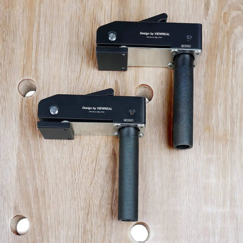 Two Pack Three Quarter Inch Aluminum Alloy Bench Dog Clamps For Woodworking positioned on a wooden workbench with holes.