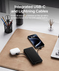 Heavy Duty 10K Portable Charger Power Bank With Integrated Usb C And Lightning Cables To Keep Your Phone Fully Juiced Using Rapid 23W Fast Charging Road Trip Essential charging an iPhone and AirPods on a desk.