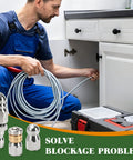 Three Pack Sewer Jetter Nozzle Kit With Stainless Steel Rotating Button Nose And Fixed Nozzles For One Quarter Inch Quick Connect Wands Up To Five Thousand PSI Perfect For Clearing Clogs In Drains Pipes And Sewer Lines With Your Pressure Washer shown in use under a sink by a worker with a hose.