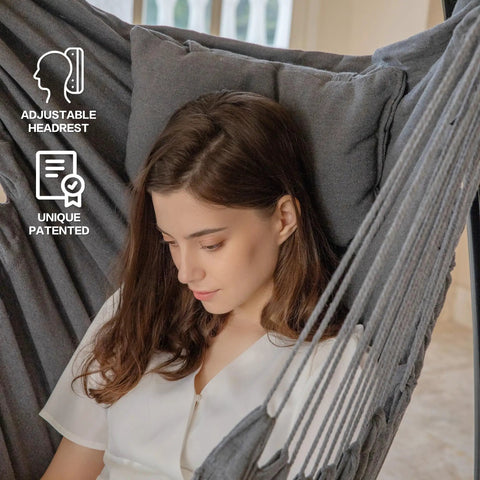 Woman sitting in dark gray hammock chair with adjustable headrest indoors, part of Hammock Chair With Stand For Indoor And Outdoor Use