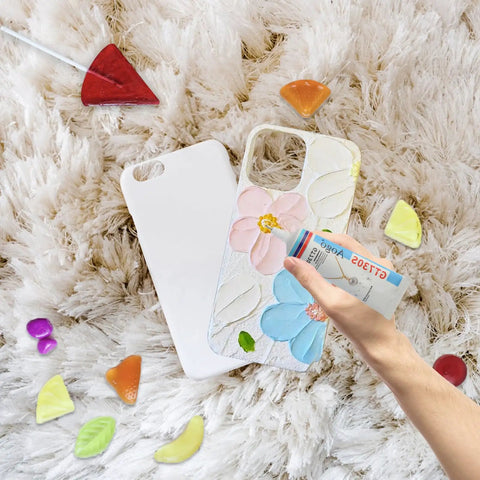Phone case with floral design and a hand holding a credit card on a fluffy surface surrounded by colorful nuggets.