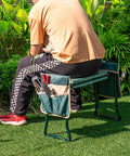 Man sitting on Foldable Garden Kneeler And Seat With 8 Inch Wide EVA Foam Pad, Heavy Duty Garden Stool With Two Big Tool Pouches in garden.