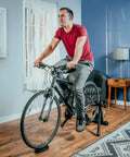 Front Wheel Riser Trainer Block With Anti Slip Design For Indoor Bike Training Fits Stationary Mountain And Road Bikes Natural Riding Position Setup For Home Gym Rides shown in home setting with cyclist using bike.