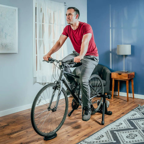 Front Wheel Riser Trainer Block With Anti Slip Design For Indoor Bike Training Fits Stationary Mountain And Road Bikes Natural Riding Position Setup For Home Gym Rides shown in home setting with cyclist using bike.