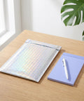 Glitter Bubble Mailers 30 Pack Tear Resistant Shipping Bags for jewelry makeup gifts next to notepad on desk