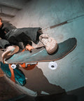 Person performing skateboard trick indoors with graffiti backdrop, showcasing intense jump and dynamic movement.