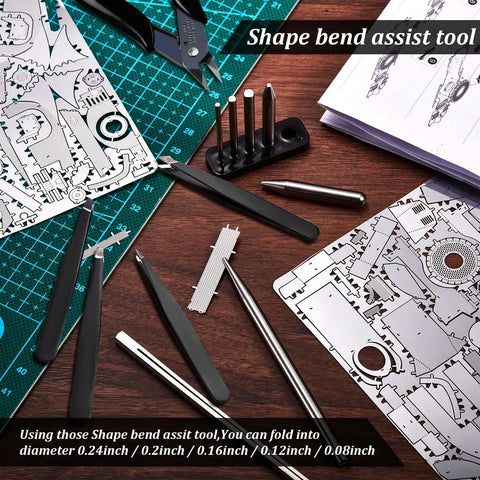 12 Piece Metal Model Tool Set For DIY 3D Puzzles Includes Long Edge Bending Tools Tab Twisting Tool Cone Bend Aids Clipper And Four Metal Tweezers arranged on a wooden table with metal puzzle sheets and instructions.