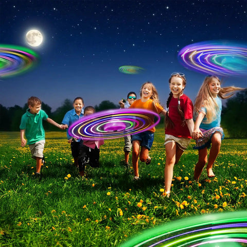 Children playing at night with LED Flying Saucer Toys 4 Pack With Built In Flashing Lights For Kids Outdoor Glow In The Dark Night Light Trails Party Favors Ages 4 8 12 Totally Lit For Group Games And Parties Outdoors Or Indoors.