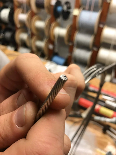 Close-up of hands holding a steel cable, ready for cutting with a 7 Inch Wire Rope Cutter For Railing And Cable Installations With Induction Hardened Blades That Cut Aircraft Cable Seismic And Structural Cables Up To Three Sixteenths Of An Inch Steel Copper Or Aluminum Without Any Frayed Edges