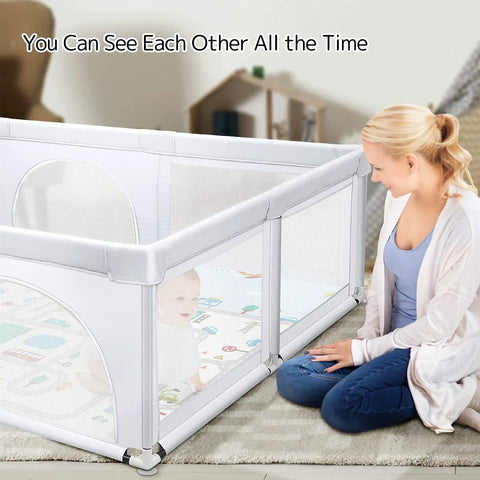 Mother watching baby in Extra Large Baby Playpen With Mat 79 By 71 Inches For Toddlers And Infants Safety Gate Play Yard In Light Gray.