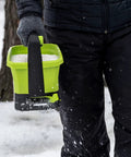 Person using 20-Volt Cordless Handheld Seed And Fertilizer Spreader For Yard Work With Adjustable Spreading Rate Dial on snowy day
