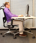 Person sitting at desk on office chair with solid silicone caster cups no slip furniture wheel stoppers for all floors and wheels.