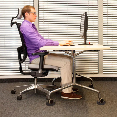 Person sitting at desk on office chair with solid silicone caster cups no slip furniture wheel stoppers for all floors and wheels.