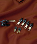 Universal Zipper Repair Kit 6 Pack With Replacement Sliders And Seam Ripper for coats and jackets on brown fabric