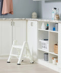 Two Step Folding Foot Stool, 14 Inch High, 300 Pound Capacity in a kitchen setting, grab and go lightweight design, shown open.