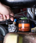 Hand using Beefy 3 Jaw Magnetic Oil Filter Wrench for Tight Spaces Heavy Duty Oil Filter Remover Fits 2.4 to 3.6 Inch Filters 3/8 Inch Drive Adjustable Auto Tool for DIYers and Pros to remove oil filter in engine bay