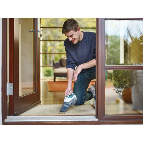 Man using Cordless Dustbuster Handheld Vacuum For Car And Home With Rechargeable Lithium Power And Boss Level Suction indoors.