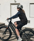 Person riding a modern black electric bike outdoors.